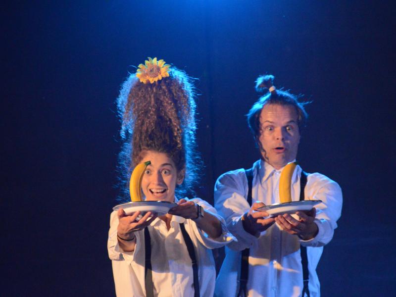 Billedet viser to klovne med hver sin tallerken med en banan strakt frem foran sig